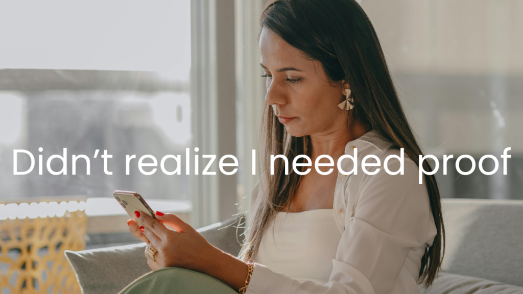 Homeowner standing in a living room looking at their phone, appearing thoughtful about documenting personal belongings